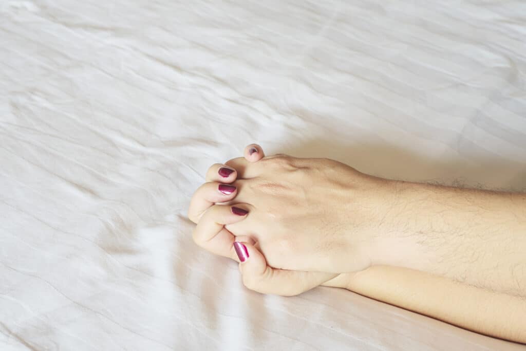 man holding woman hand white bed couple sexual concept