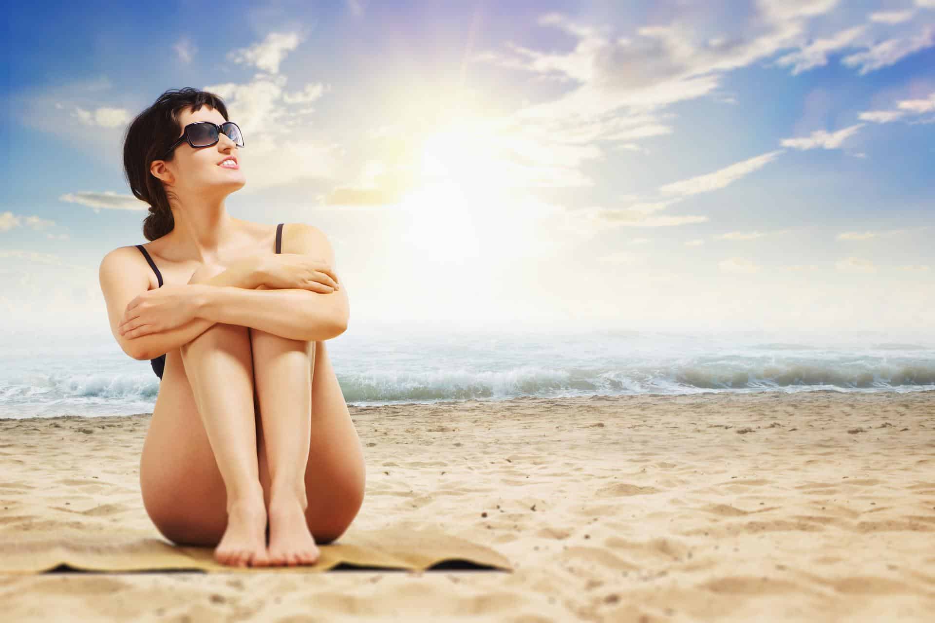 sahilde oturan güneş gözlüklü kadın