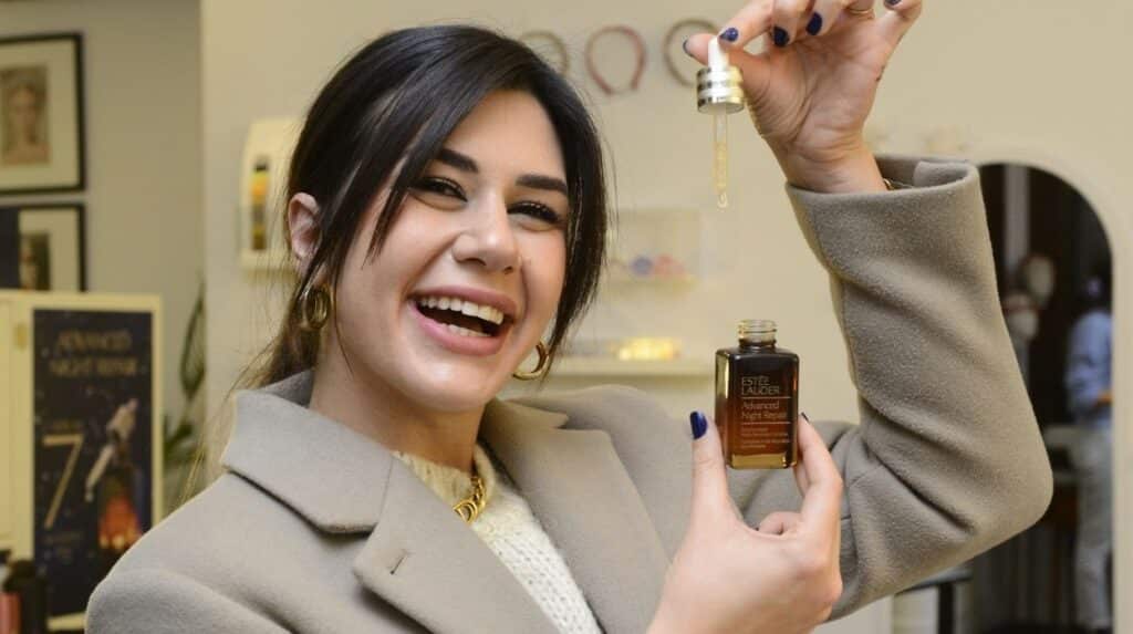 estée lauder kahverengi şişeyi elinde tutan kadın